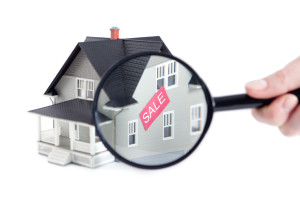 Hand holding magnifying glass in front of the house